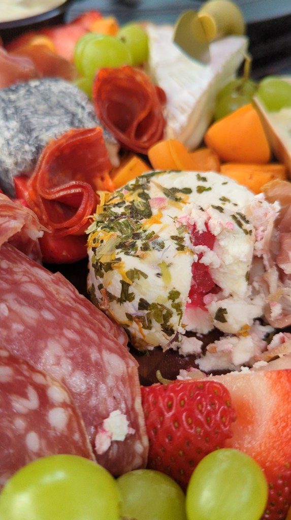 French cheese close-up on a charcuterie board; covered in flowers and herbs